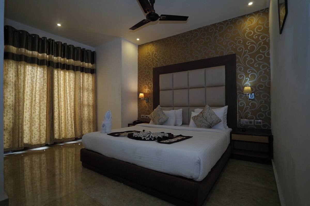 A modern bedroom with a large bed, a ceiling fan, and decorative wall panels.