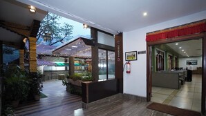 A hotel lobby with a reception desk, seating area, and a view of the outdoor patio area. - Terrace Valley Hotel (Gangtok)