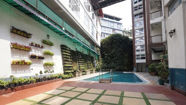 A courtyard with a swimming pool, potted plants, and a tiled floor. - Terrace Valley Hotel (Gangtok)