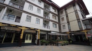 A multi-story building with a courtyard, featuring a central entrance with steps, potted plants, and string lights. - Terrace Valley Hotel (Gangtok)