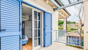 A blue sliding door leading to a room with a bed and a view of a garden and houses. - Vacation home Mala by Interhome (Murter/Murter)