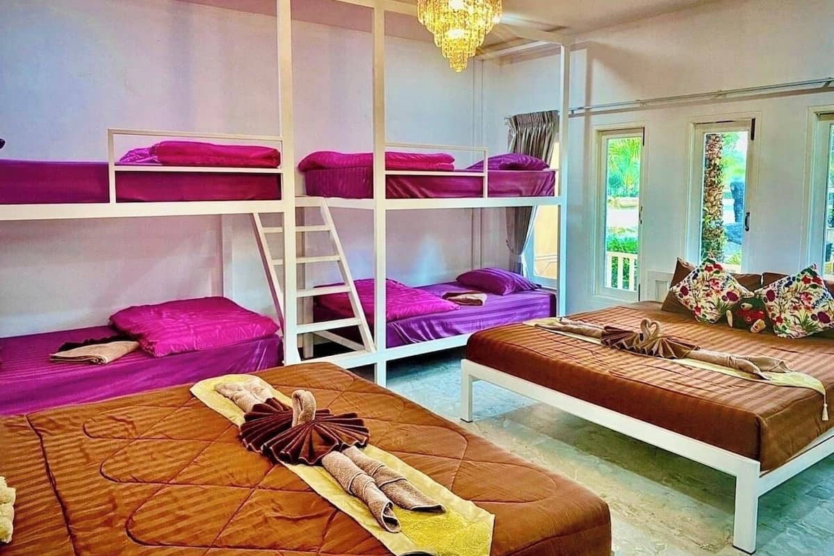 Ett rum i studentkorridorsstil med våningssängar och en bäddsoffa, en kristallkrona och utsikt över grönområden utanför.