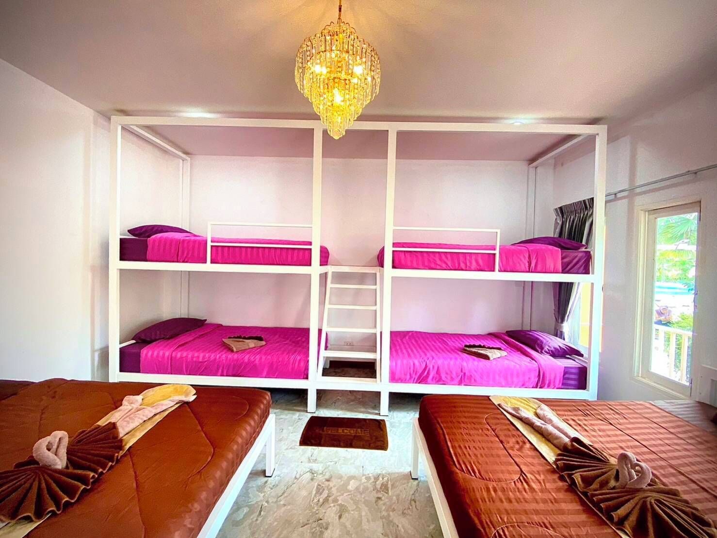 Une chambre avec un lit superposé, un lustre, une échelle et une fenêtre avec des rideaux.