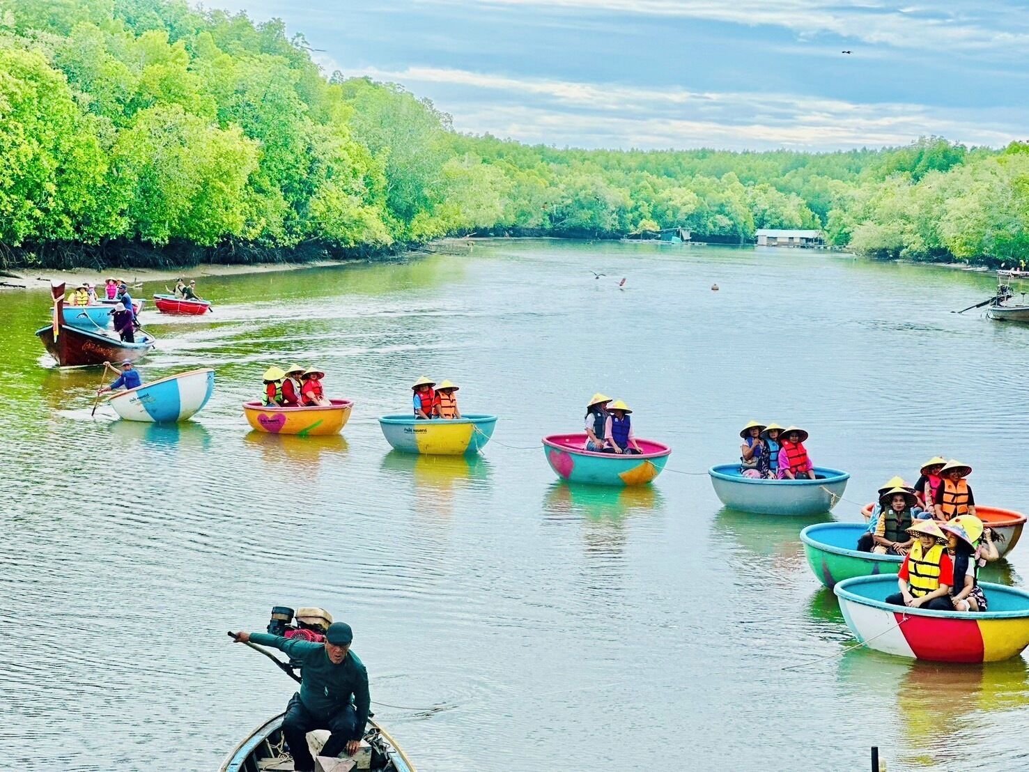 A group of colorful boats on a calm river surrounded by lush greenery.
