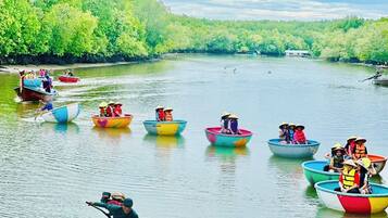 A group of colorful boats on a calm river surrounded by lush greenery.
