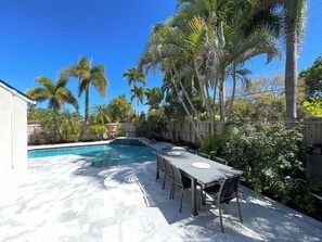 Un patio trasero con piscina, una mesa de comedor y sillas.
