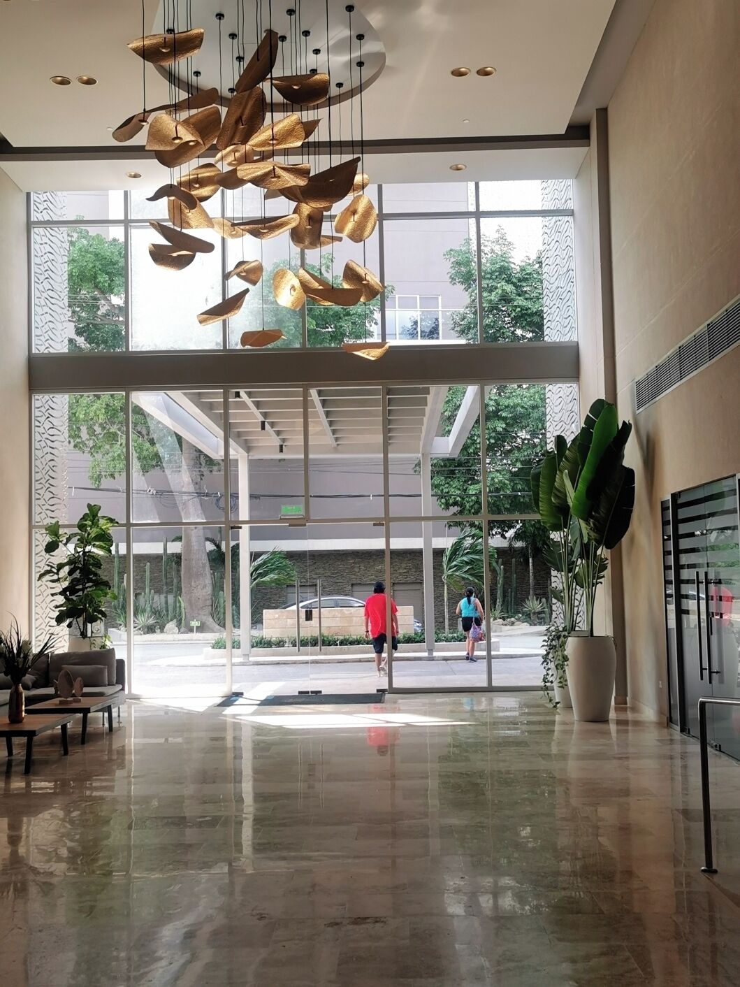 A spacious lobby with a modern chandelier, large windows, and a wet floor.