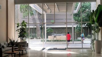 A modern lobby with a glass entrance, a sofa, a coffee table, and potted plants.