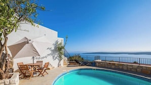 A pool area with a view of the sea, outdoor furniture, and a white building. - Luxury Villa in Zavala w/pool (Zavala, Jelsa)