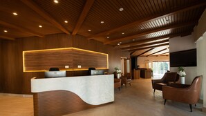Un comptoir d’accueil avec un revêtement en bois et un plan de travail en marbre, entouré de fauteuils en cuir et posé sur un parquet.