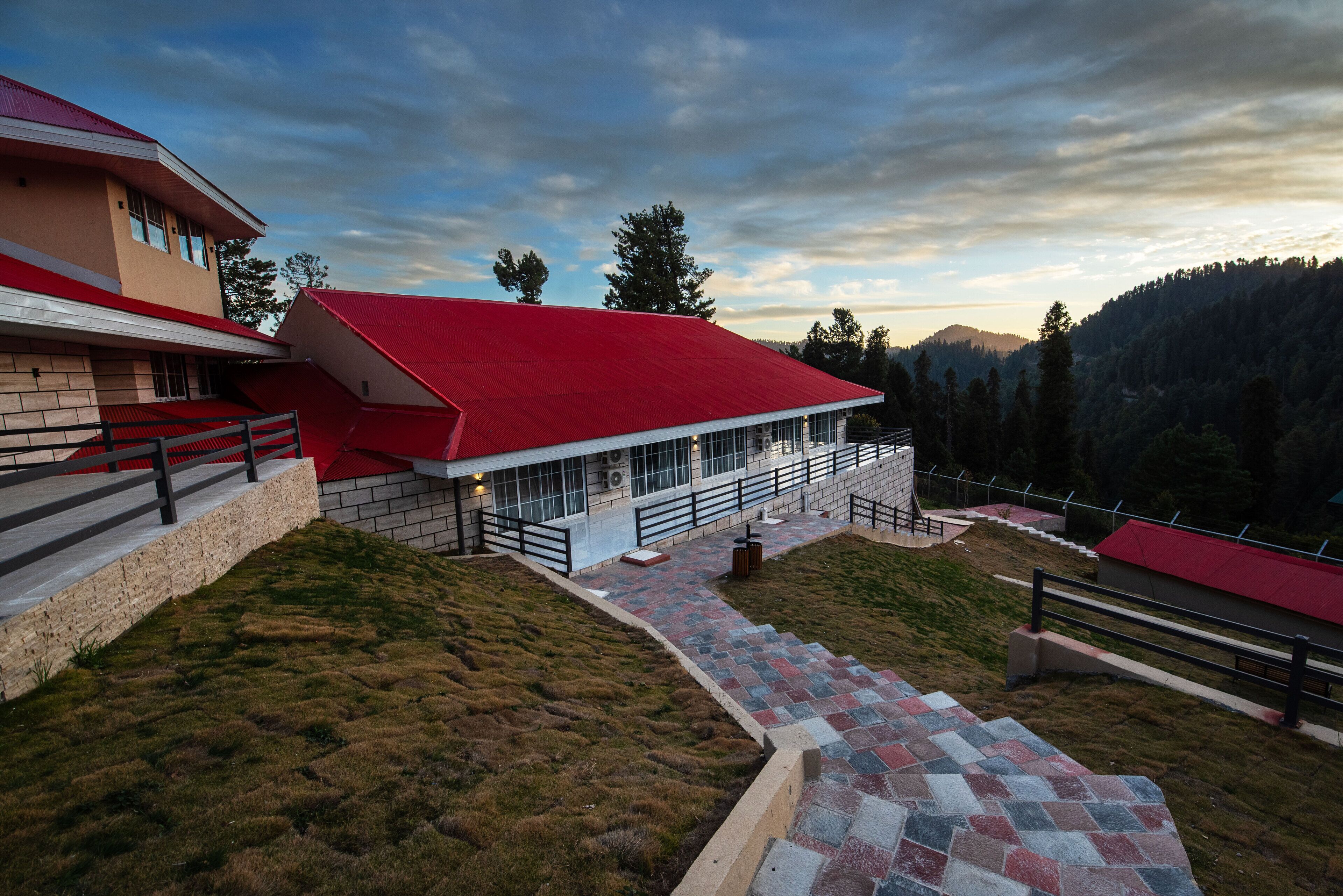 A modern building with a red roof, a glass facade, and a stone base.