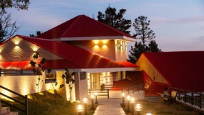 Un bâtiment moderne avec un toit rouge, un chemin en briques menant à l’entrée et des places assises à l’extérieur.