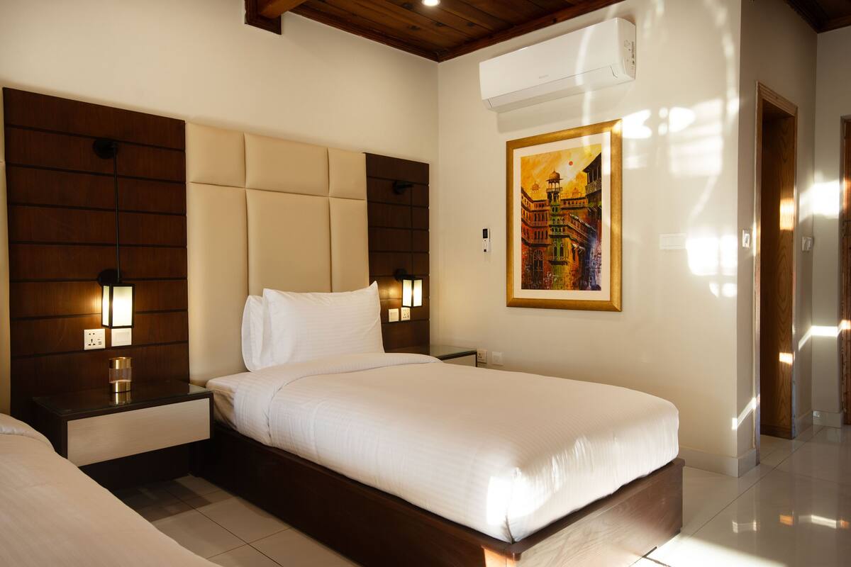 Une chambre d’hôtel avec un grand lit, une tête de lit en bois, des lampes de chevet et un tableau encadré au mur.