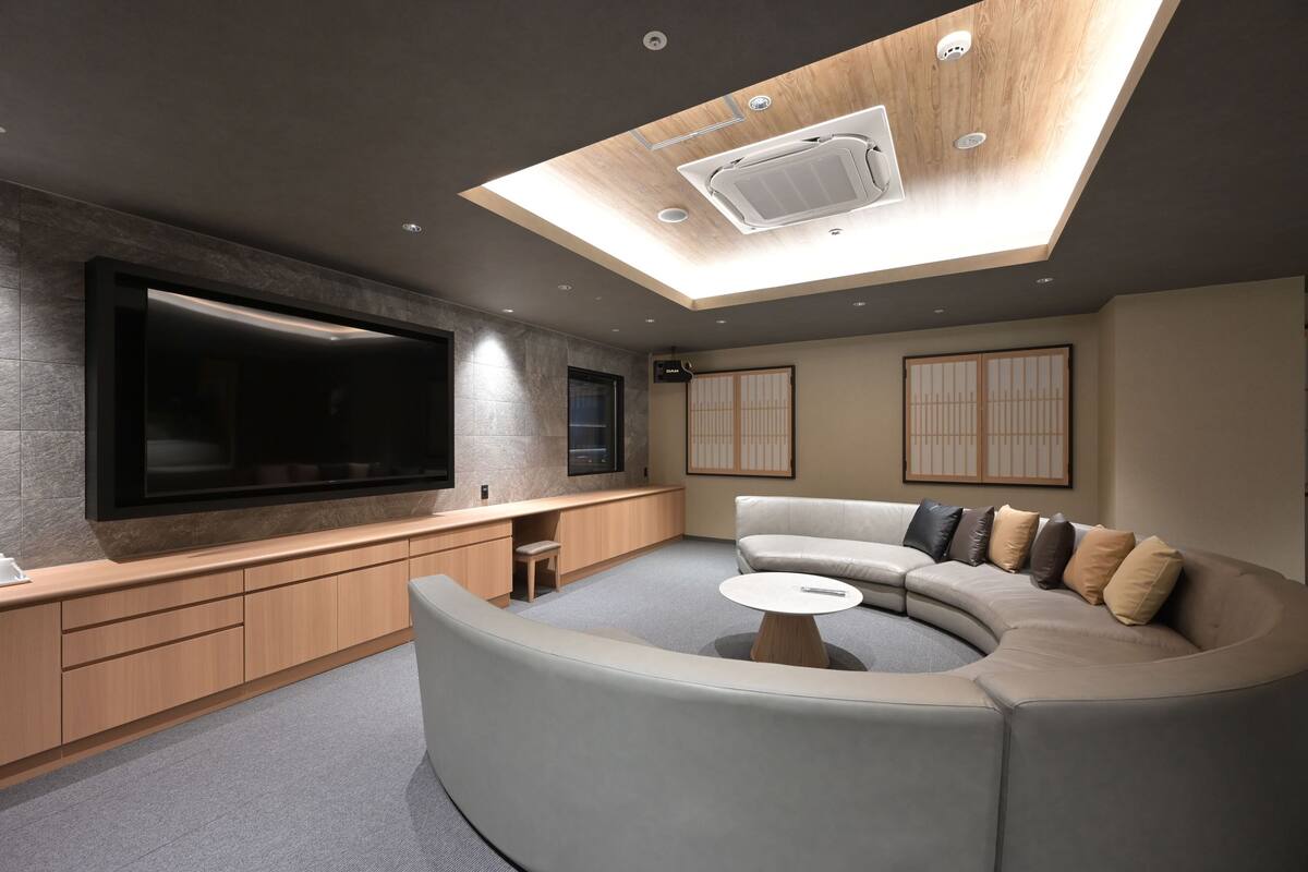 A modern living room with a large flat-screen TV, built-in seating, and a skylight.