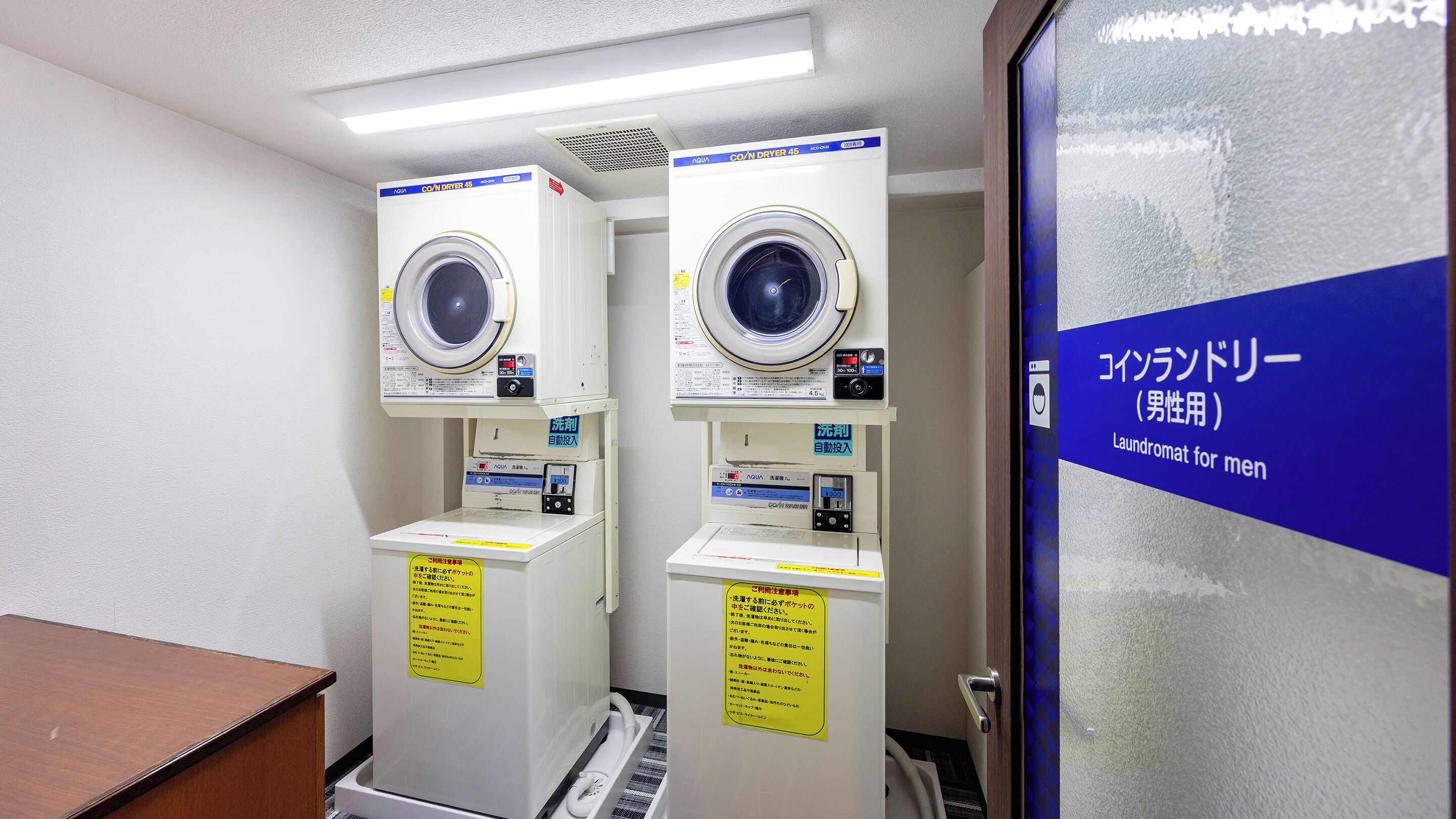 A laundromat with two washing machines and a sign indicating it's for men.