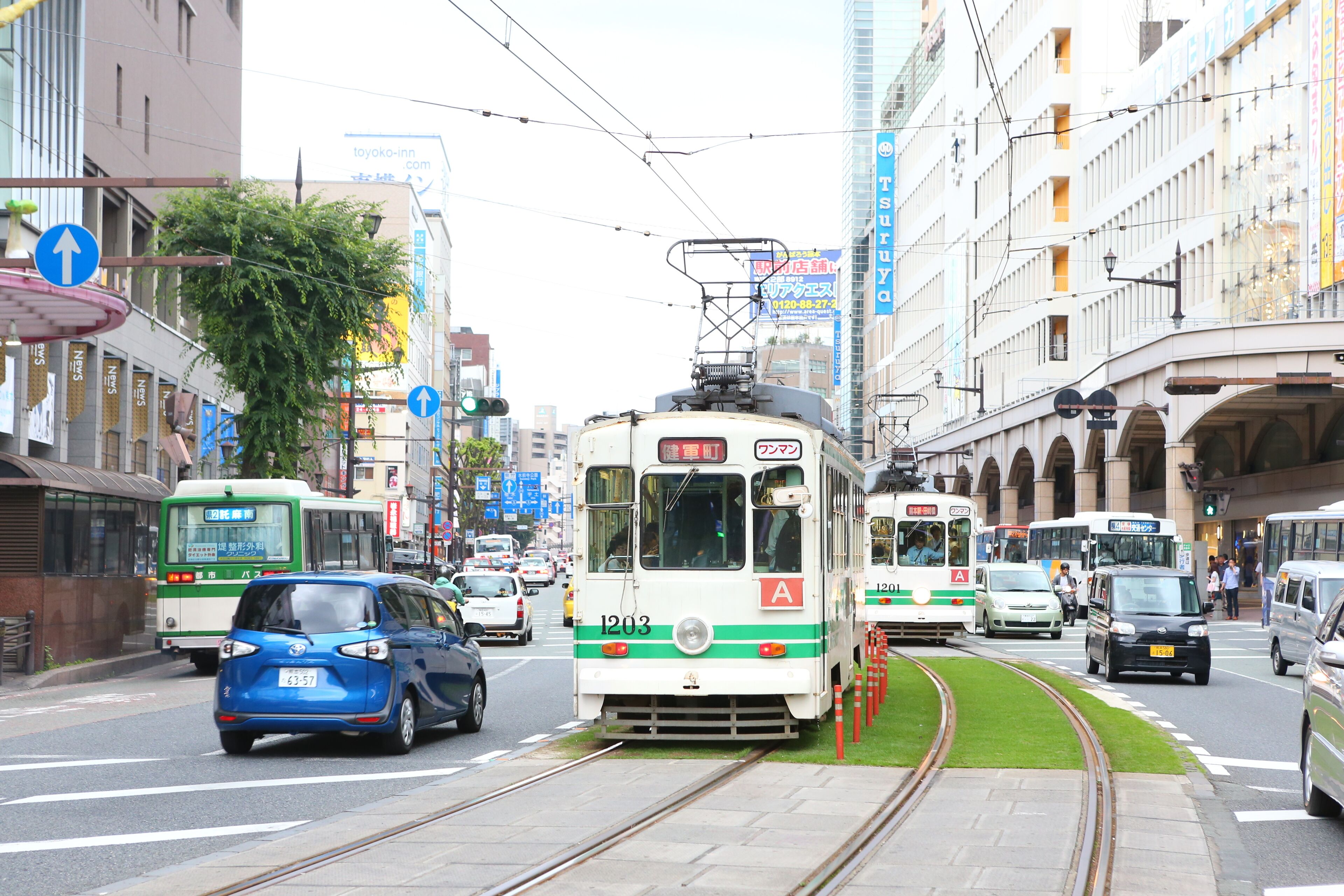 Una bulliciosa calle urbana con vías de tranvía, vehículos y edificios.