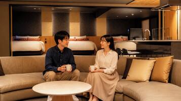 A modern hotel room with a sofa, a small round table, and a bed with a headboard.