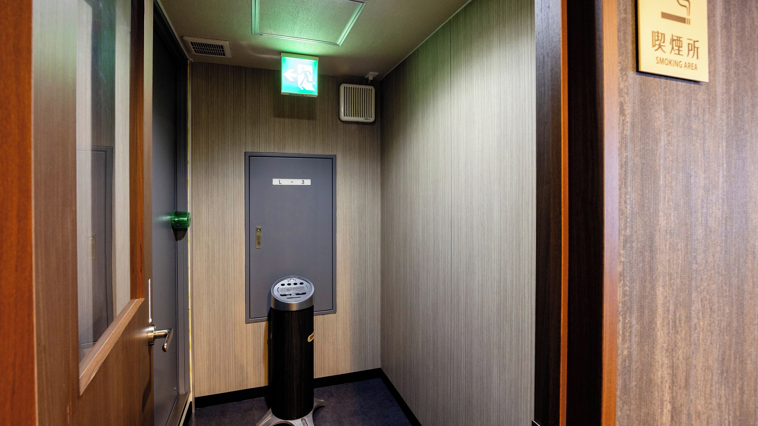 A narrow hallway with a door labeled 'L-3' and a smoking area sign on the right wall.