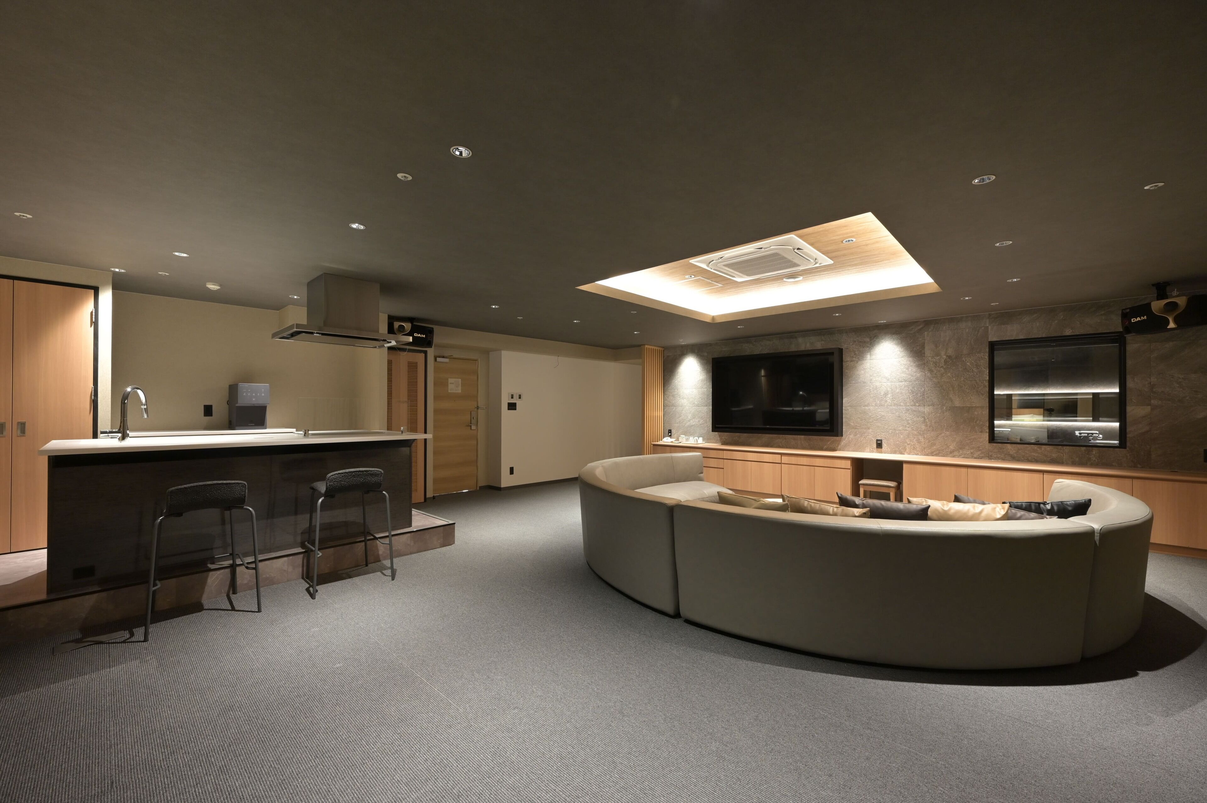 A modern kitchen with a central island, bar stools, and a built-in oven.