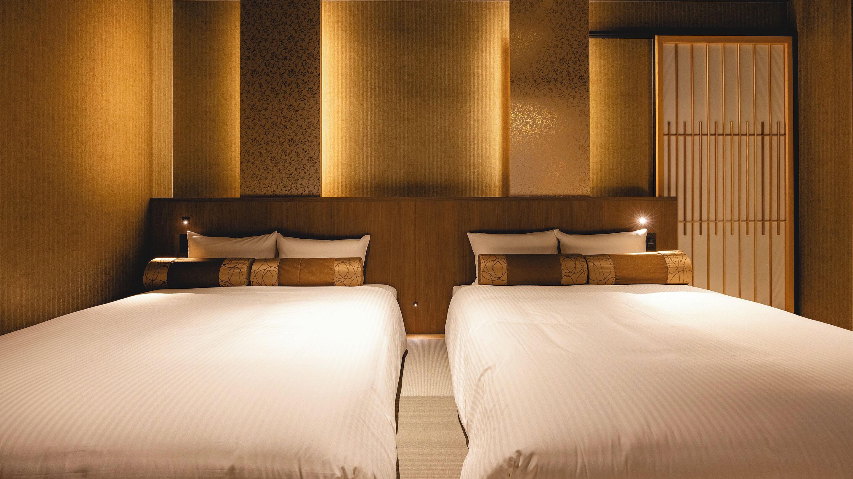 A hotel room with two beds, a wooden headboard, and a wardrobe.