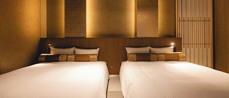 A hotel room with two beds, a wooden headboard, and a wardrobe.