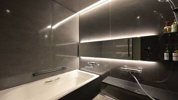 A modern bathroom with a large bathtub, a separate shower area, and a vanity with a mirror.