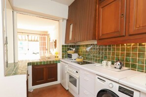 Een koelkast, een oven, kookgerei, borden en bestek