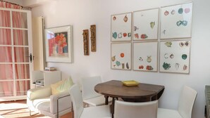 A dining area with a round table, white chairs, and a framed botanical illustration on the wall. - Maison de pêcheur with Air-conditioned and mooring, Wi-Fi, for 7 persons, near the beach (PORT GRIMAUD)