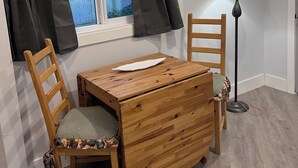 A small room with a wooden table and two chairs, a floor lamp, and a window with curtains. - Salida Cottage (Salida)