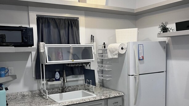 A compact kitchen with a sink, microwave, and refrigerator, featuring a wooden table and grey cabinets. - Salida Cottage (Salida)