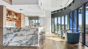 A modern kitchen with a marble island, wooden shelves with bottles, and a bar area with stools. - Centre of Brisbane at RiverFront (Brisbane City)