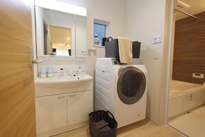 Ein modernes Badezimmer mit Waschmaschine, Waschbecken und Spiegel.