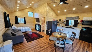 A cozy cabin with a living room, dining area, kitchen, and a ceiling fan.