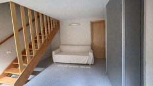 A room with a wooden staircase, a white sofa, and a door. - Borgo Agapito in the heart of Marciana (Marciana)