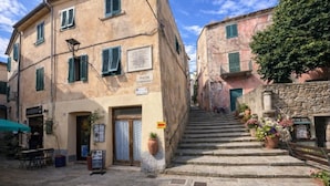 A narrow street with stone steps leading to a building with a sign reading "PIAZZA". - Borgo Agapito in the heart of Marciana (Marciana)