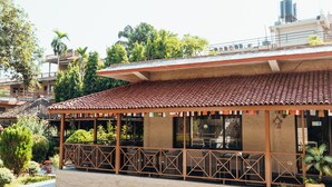Ein Gebäude mit einem Ziegeldach, einer überdachten Außenlounge und einem Garten mit verschiedenen Pflanzen.