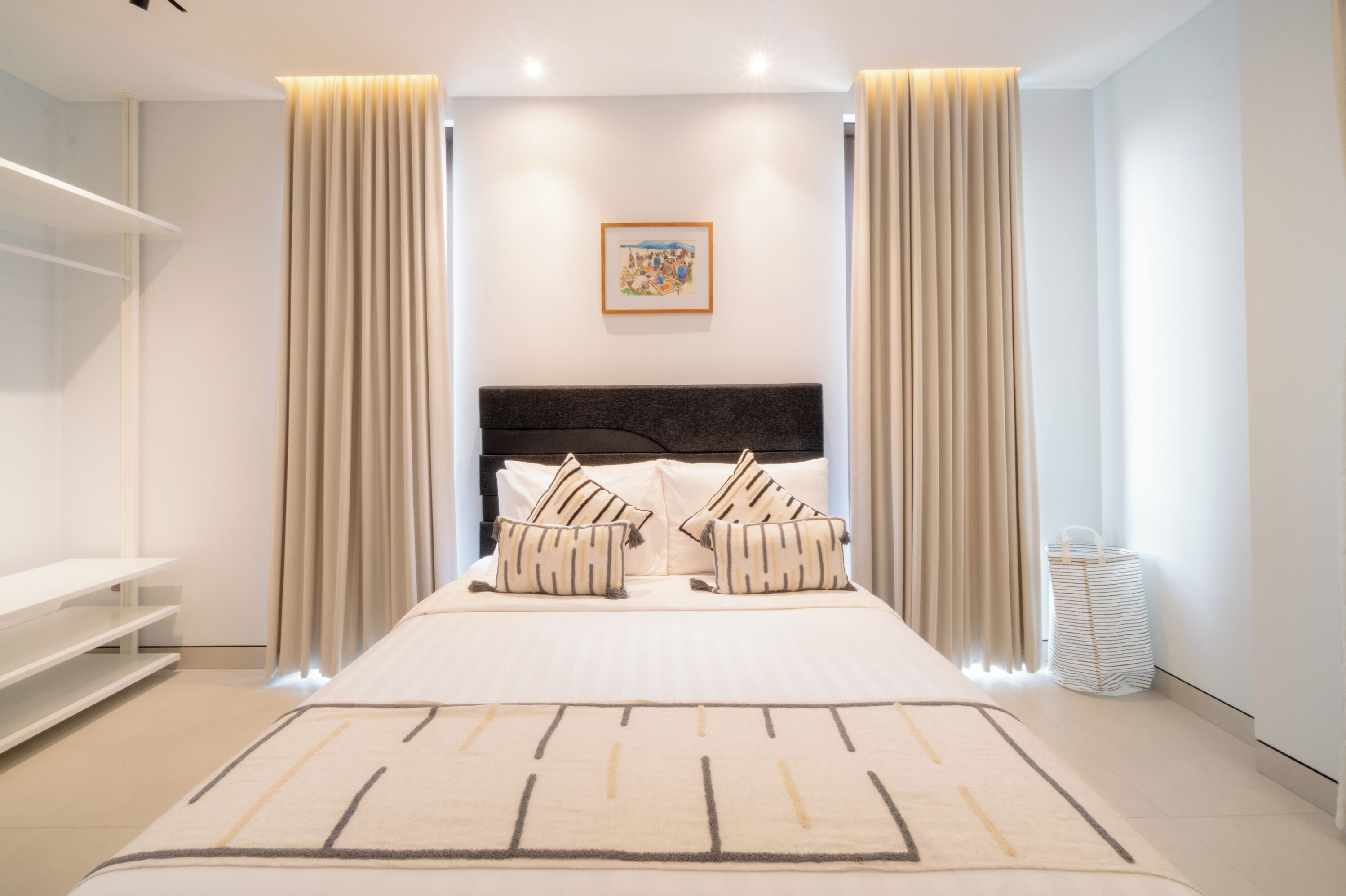Een moderne slaapkamer met een groot bed, twee nachtkastjes, een hoofdbord en een aan de muur hangend schilderij.