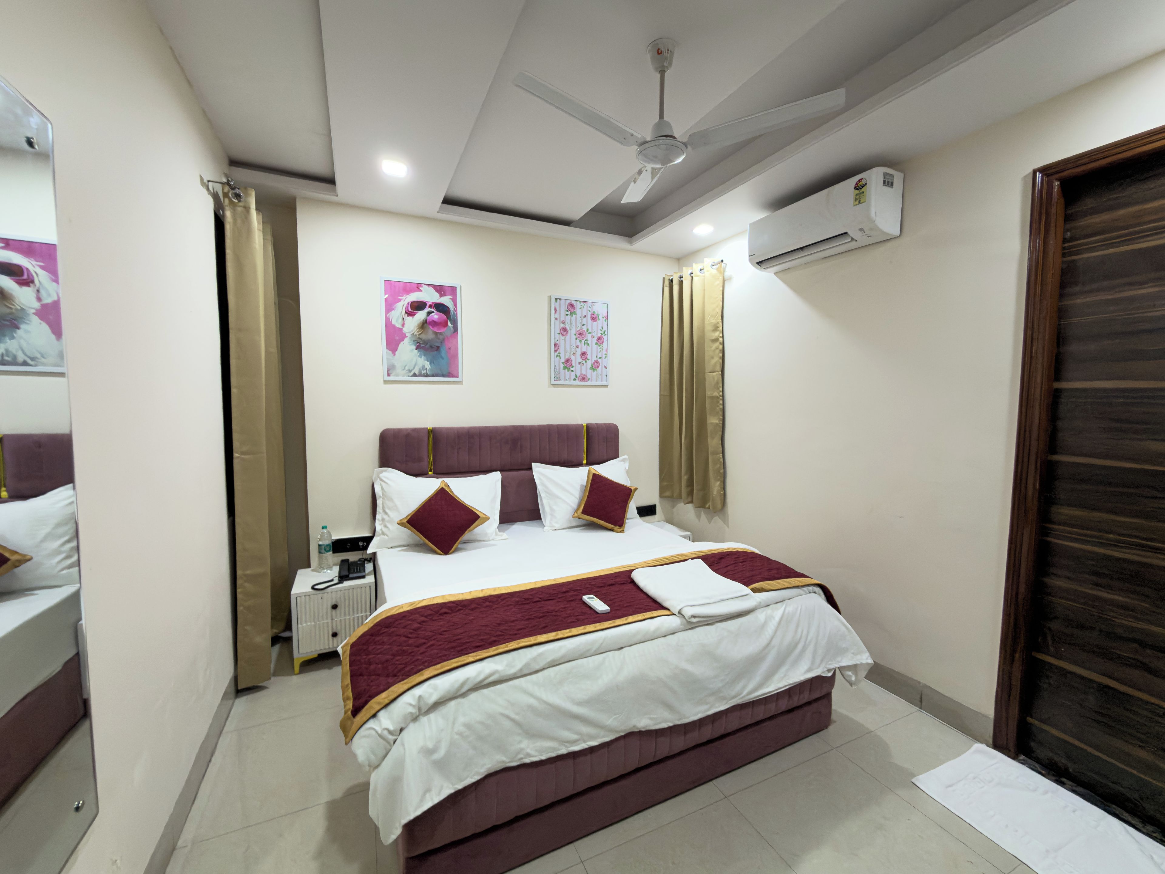 Una camera d'albergo con un letto, un comodino, una ventola a soffitto e un condizionatore d'aria.