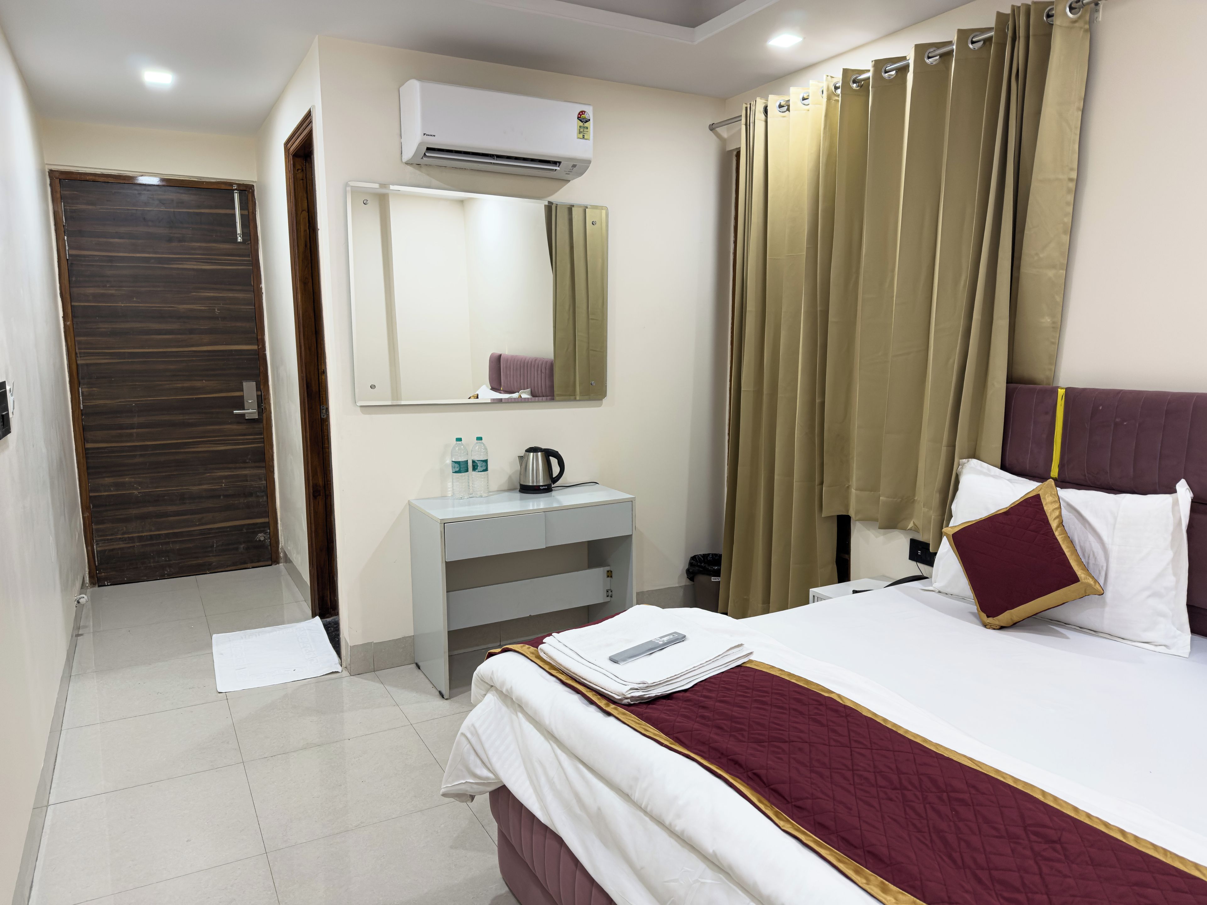 Une chambre d’hôtel équipée d’un lit, d’une table de chevet, d’un miroir, d’une armoire et d’un appareil de climatisation.