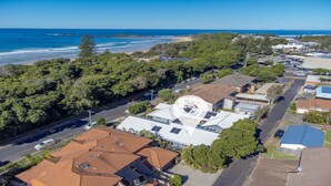 Vue aérienne d’une zone résidentielle côtière, avec des maisons, une route et une plage.