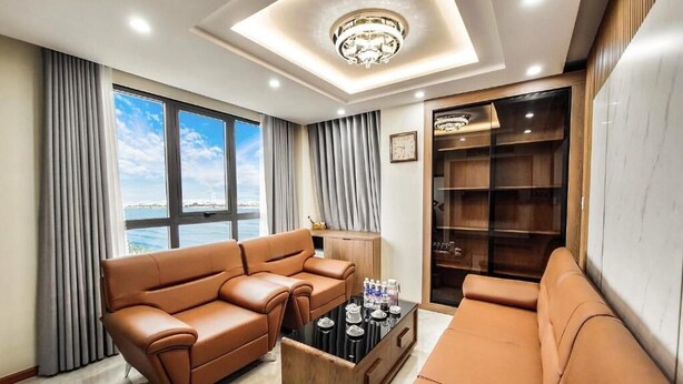 A modern living room with leather sofas, a coffee table, and a built-in bookshelf. - T.26 Hotel (Da Nang)