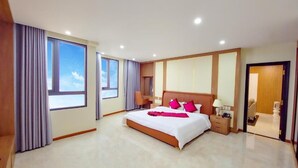 A spacious hotel room with a large bed, a desk, and a view of the sky through the windows. - T.26 Hotel (Da Nang)