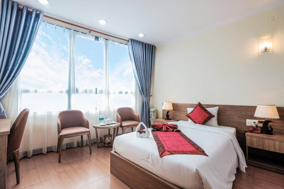A hotel room with a large bed, two chairs, a small table, and a nightstand.