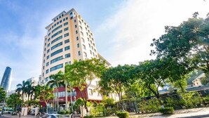 A tall building with a modern design, surrounded by trees and other buildings. - T.26 Hotel (Da Nang)