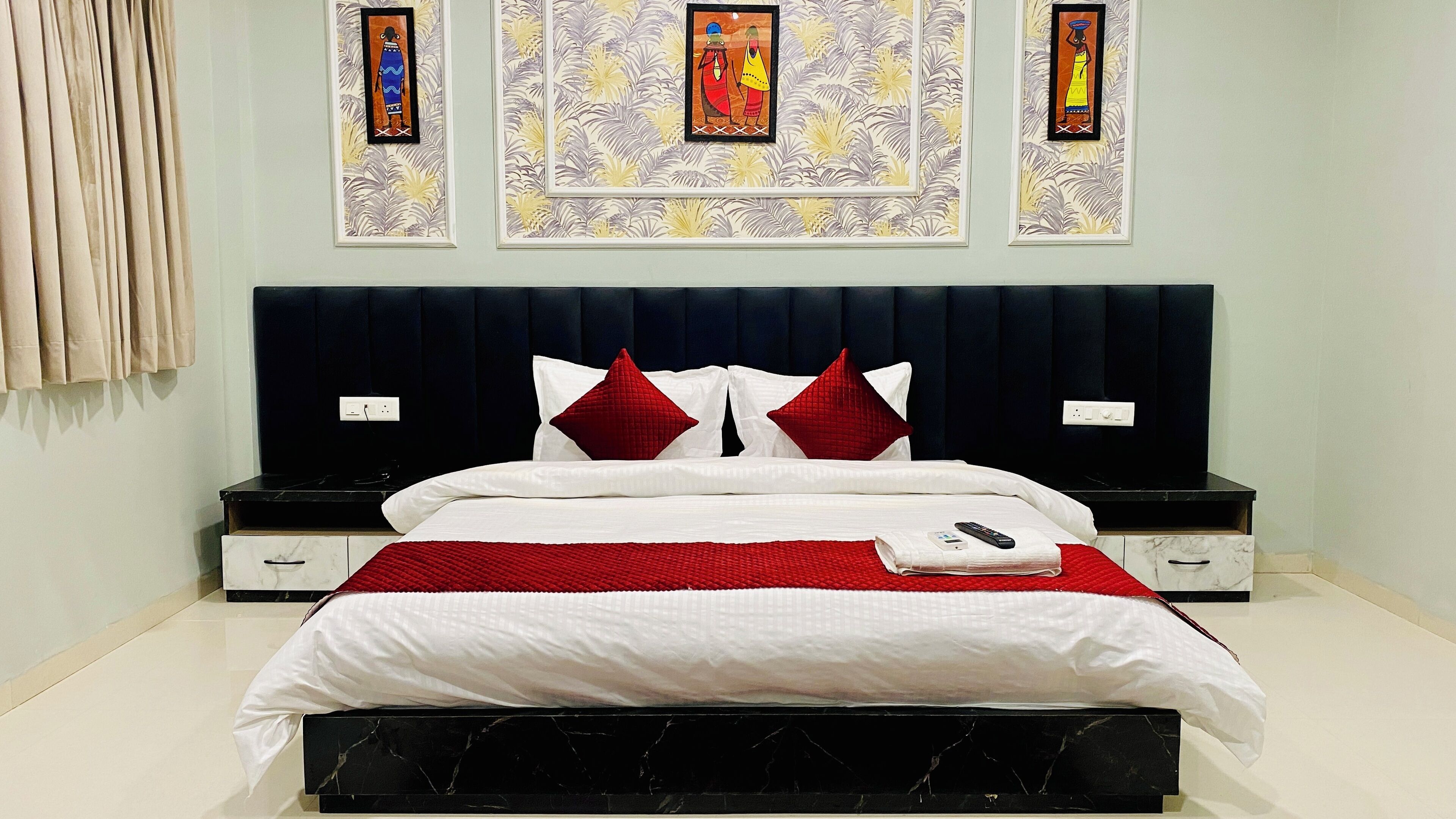 A hotel room with a bed, nightstands, and artwork on the wall.