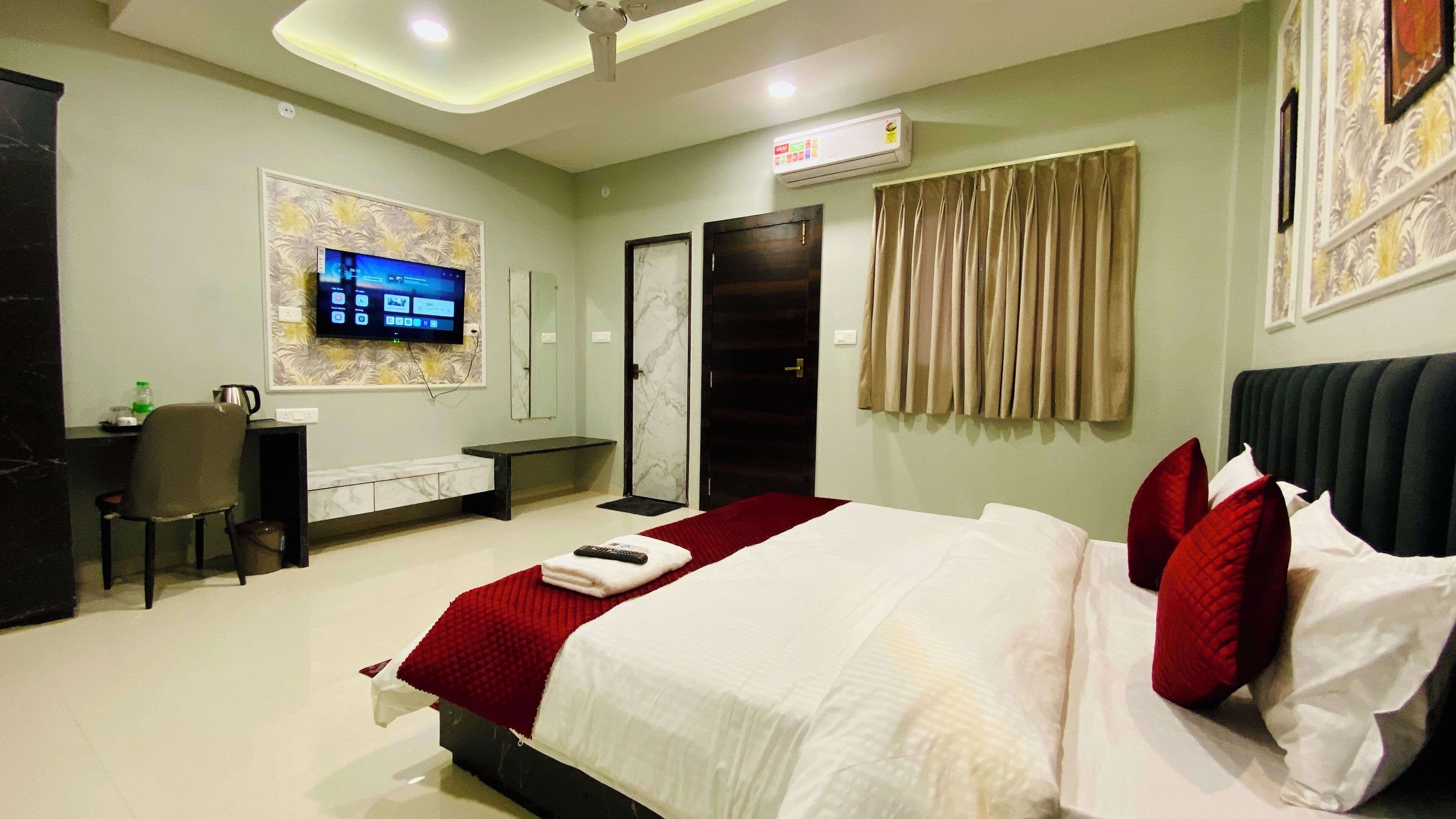 A hotel room with a bed, a desk, a chair, a television, and a bathroom door.