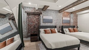Ein modernes Schlafzimmer mit zwei Betten, Backsteinwänden und einer Loft-Decke.