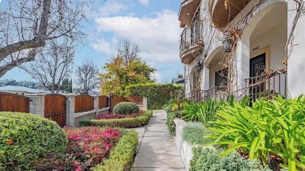 A residential building with a narrow pathway flanked by well-maintained gardens and a balcony with climbing plants. - Occidental college (Los Angeles)