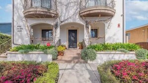 A building with three balconies, a central door, and a small garden area with various plants and flowers. - Occidental college (Los Angeles)