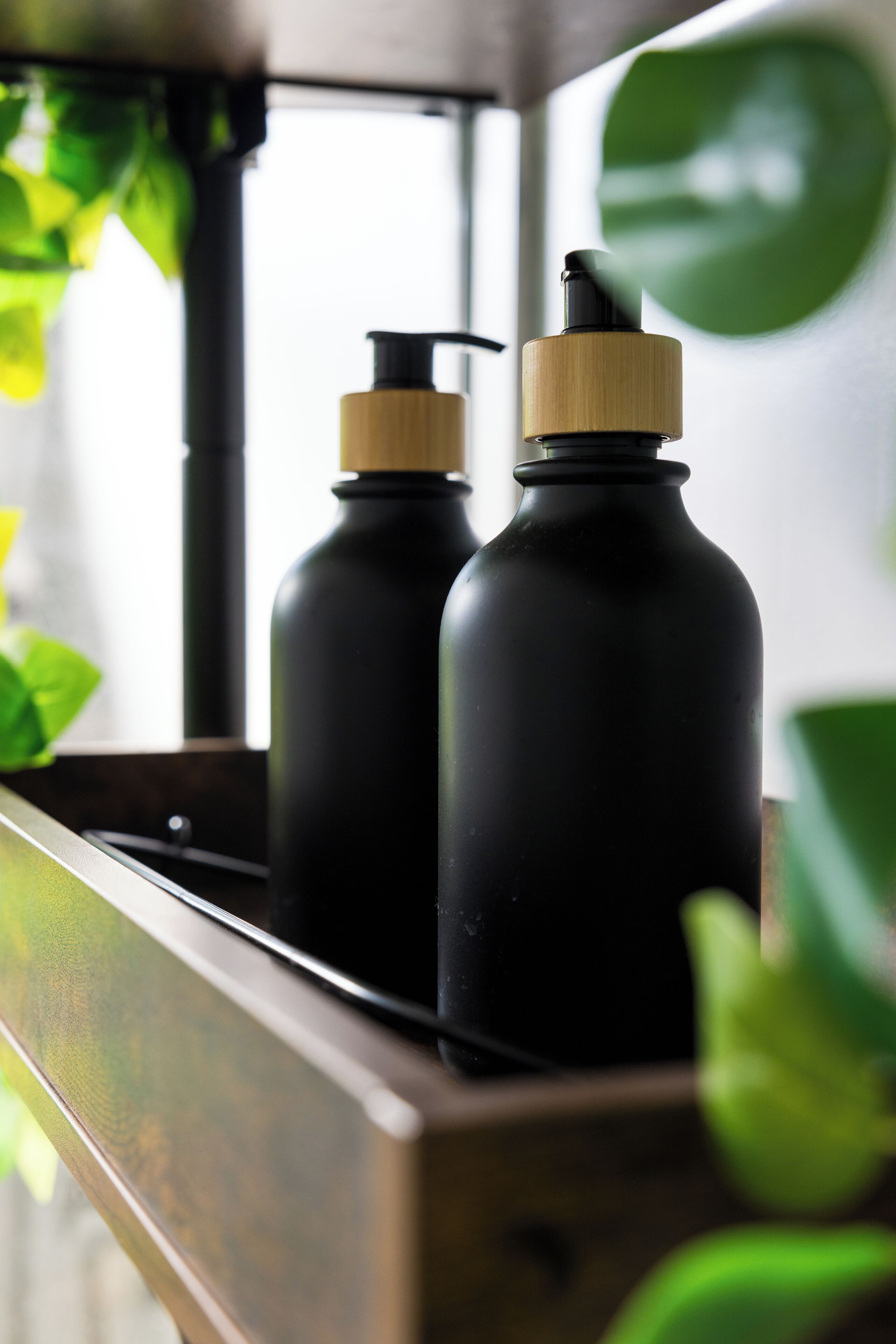Two black bottles with wooden caps in a wooden tray.
